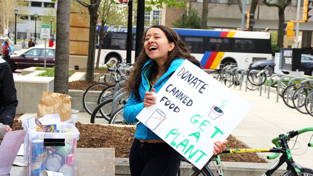 A student holds a sign asking students to donate food at the 2016 All Campus Day of Service