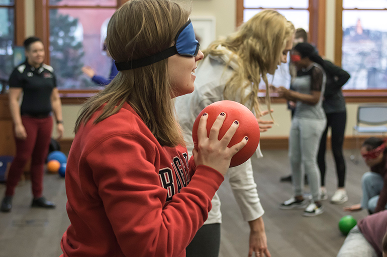 Students are blindfolded and are commanded by their partner to grab a nearby ball to throw at other blindfolded students. 